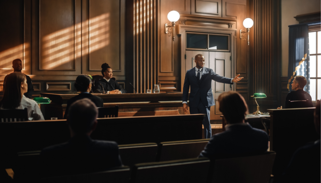 An attorney standing up in a court room gesturing toward the audience.